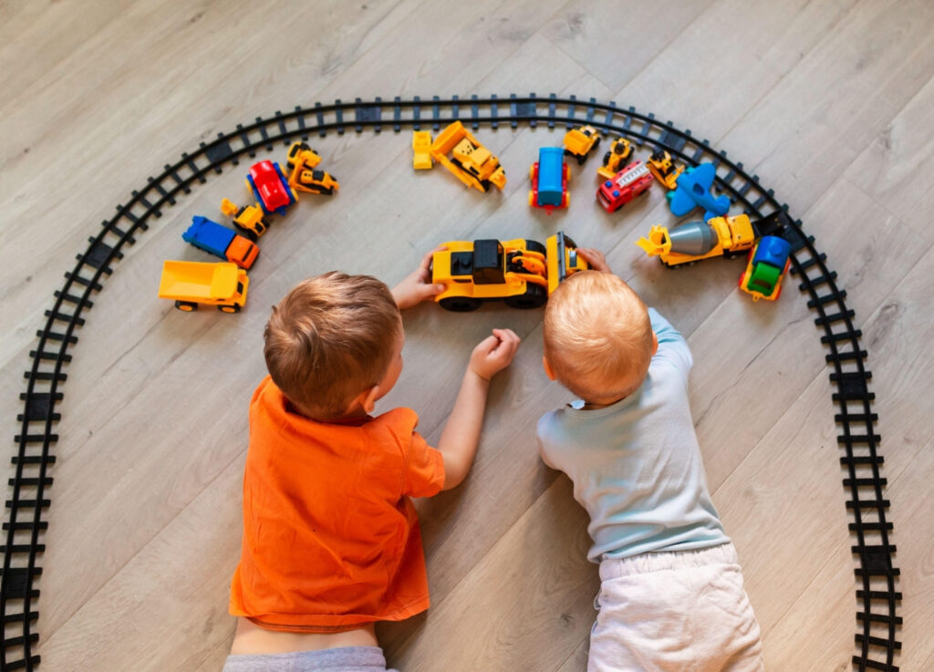 Child and baby playing with trains on the floor